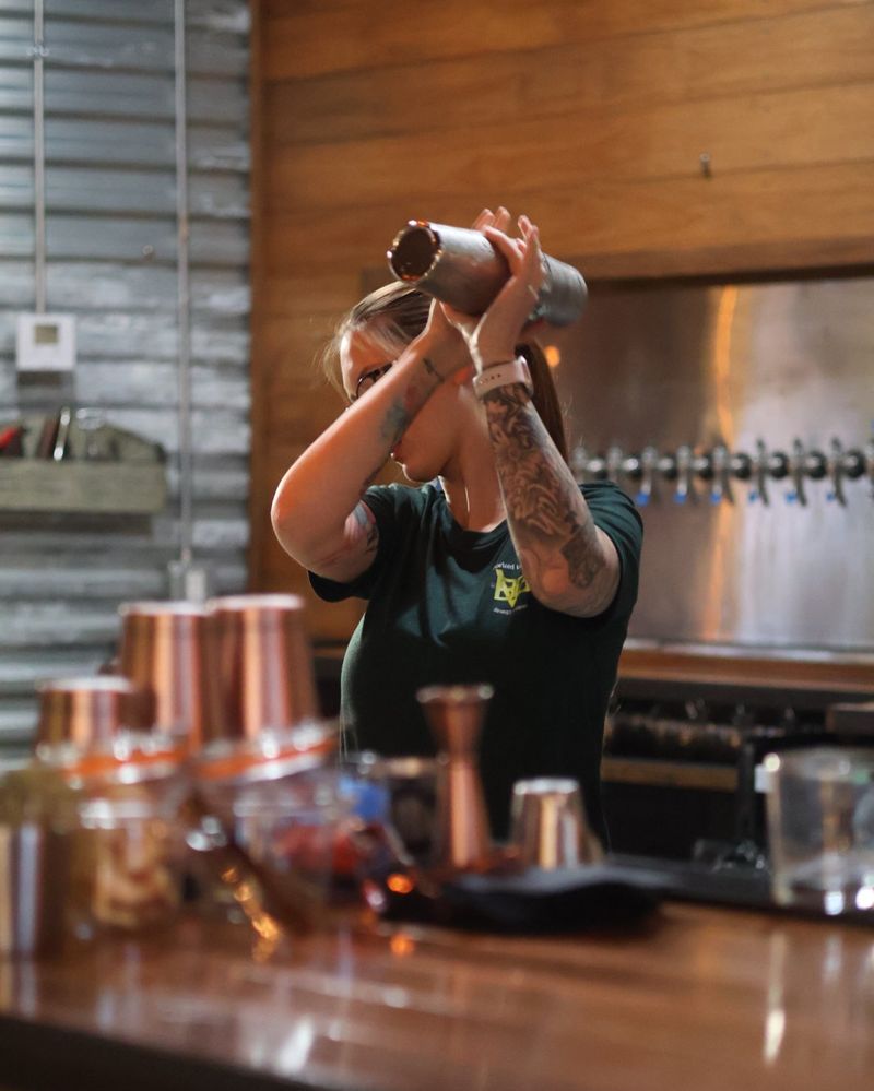 A Board Game Vault bartender shaking a cocktail behind the bar