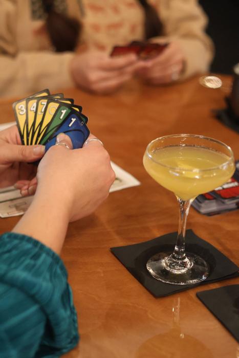 A cocktail beside a hand of cards