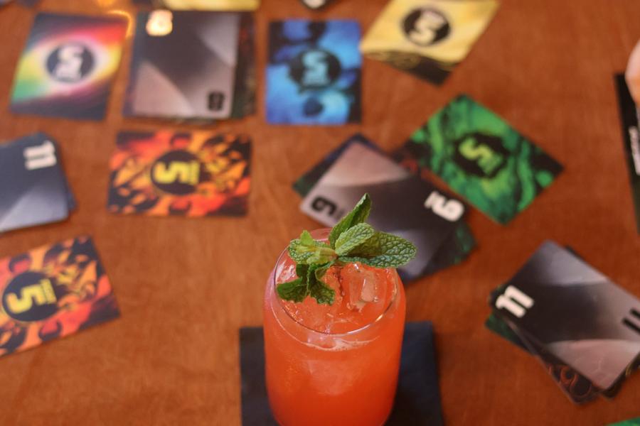 A red cocktail with fresh mint among game cards